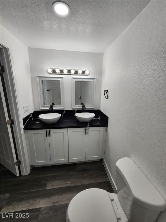 bathroom with toilet, vanity, a textured ceiling, and hardwood / wood-style flooring