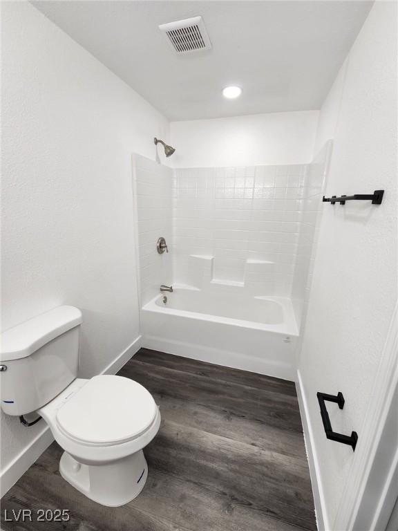 bathroom with toilet,  shower combination, and wood-type flooring