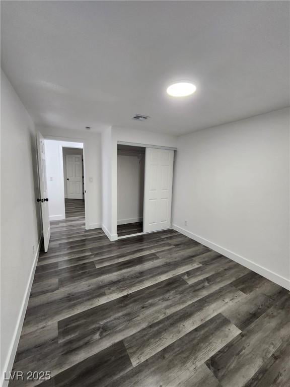 unfurnished bedroom featuring a closet and dark wood-type flooring