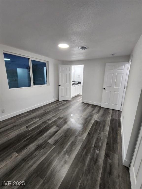 unfurnished room featuring a textured ceiling and dark hardwood / wood-style floors