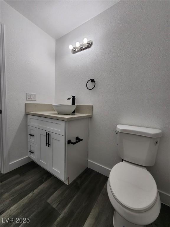 bathroom with toilet, wood-type flooring, and vanity