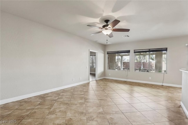 empty room featuring ceiling fan, light tile patterned floors, visible vents, and baseboards