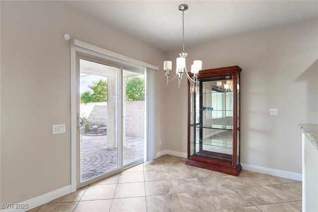 doorway with an inviting chandelier, baseboards, and light tile patterned flooring