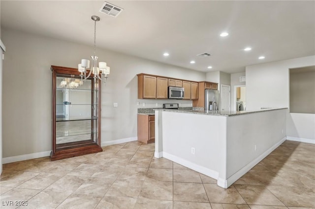 kitchen featuring visible vents, appliances with stainless steel finishes, brown cabinets, light stone counters, and pendant lighting