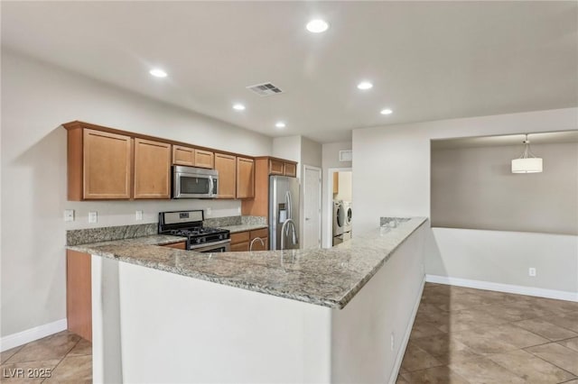 kitchen featuring visible vents, brown cabinets, independent washer and dryer, light stone countertops, and stainless steel appliances