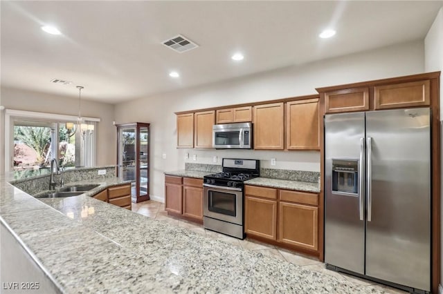 kitchen featuring stainless steel appliances, brown cabinetry, a sink, and visible vents