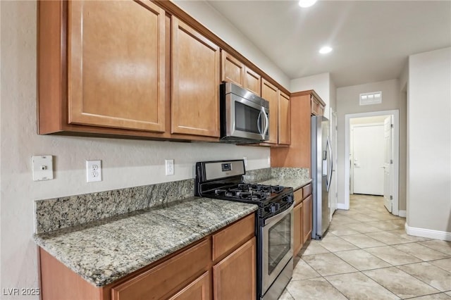 kitchen with stainless steel appliances, brown cabinetry, visible vents, and light stone counters