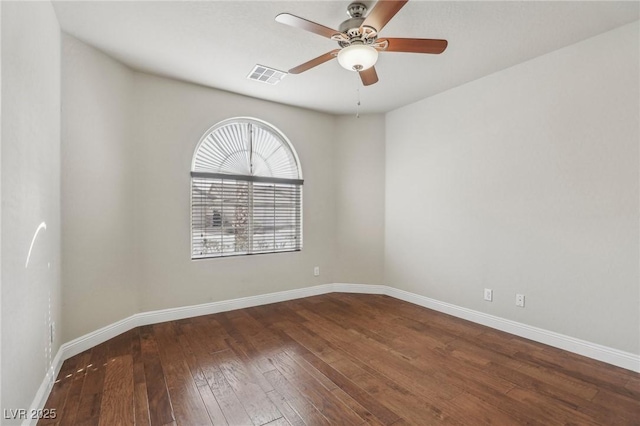 spare room featuring ceiling fan, dark wood-style flooring, visible vents, and baseboards