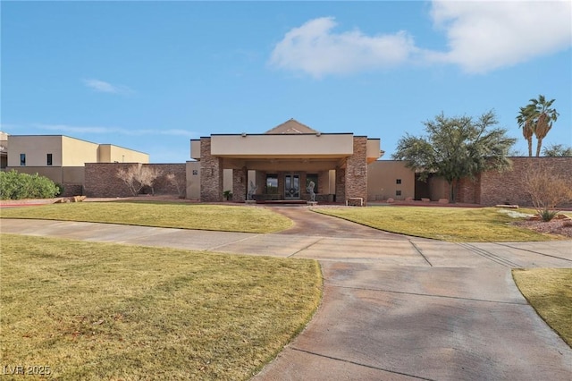 pueblo-style home with a front yard, fence, and stucco siding