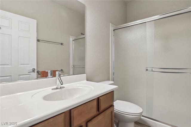 full bath featuring a stall shower, vanity, and toilet