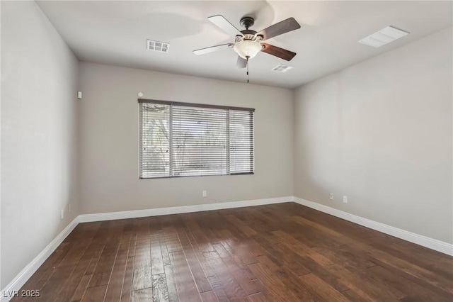 empty room featuring dark wood-type flooring, visible vents, and baseboards