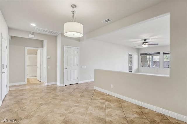 spare room with light tile patterned floors, ceiling fan, visible vents, and baseboards