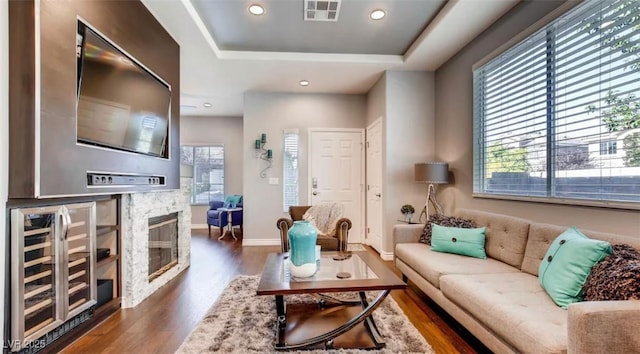 living room featuring a fireplace, beverage cooler, dark hardwood / wood-style floors, and a tray ceiling