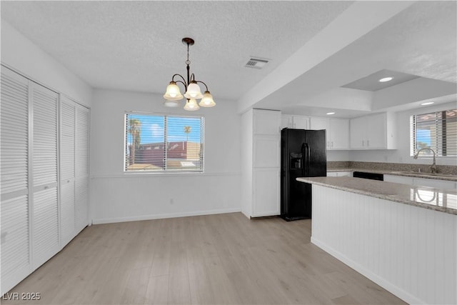 kitchen featuring black fridge with ice dispenser, hanging light fixtures, a chandelier, white cabinets, and sink