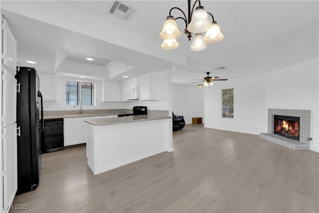 kitchen with decorative light fixtures, black appliances, sink, white cabinetry, and ceiling fan with notable chandelier