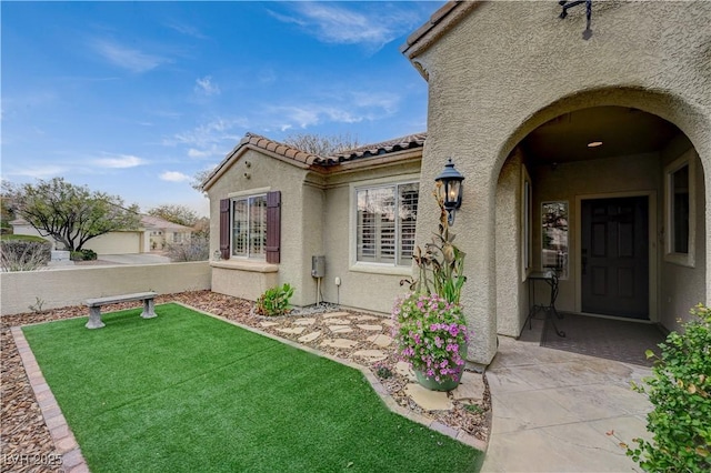 entrance to property featuring a patio area and a lawn