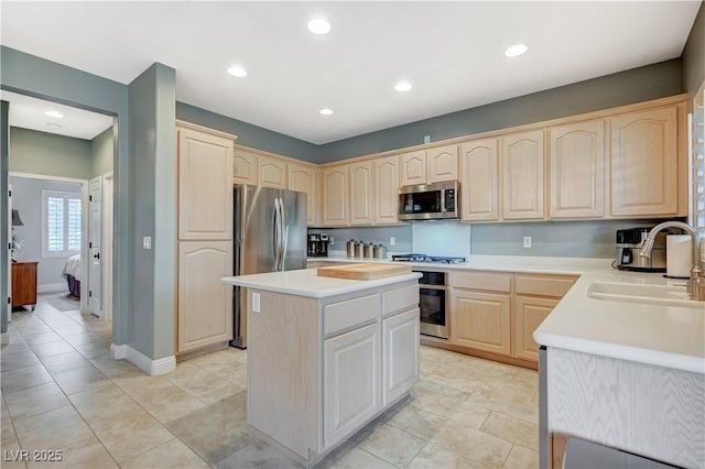 kitchen featuring appliances with stainless steel finishes, light brown cabinetry, sink, and a kitchen island