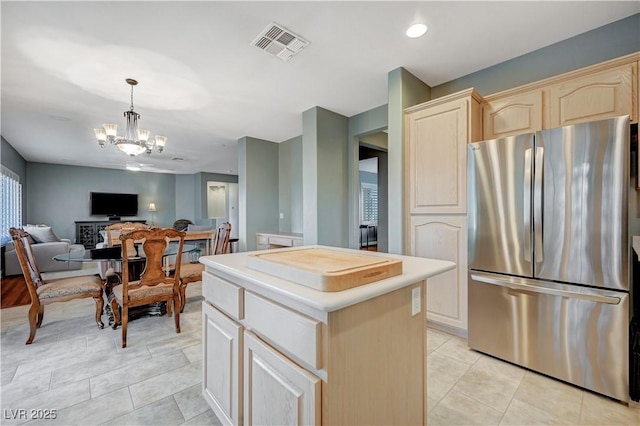 kitchen featuring a kitchen island, pendant lighting, stainless steel refrigerator, a chandelier, and light tile patterned floors