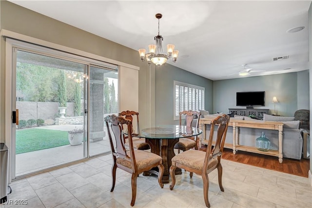 dining space with light tile patterned flooring and ceiling fan with notable chandelier