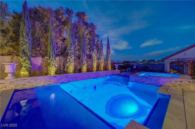 pool at dusk with an in ground hot tub