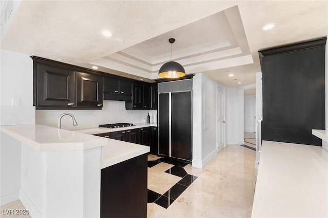 kitchen featuring a raised ceiling, hanging light fixtures, paneled refrigerator, light countertops, and gas cooktop