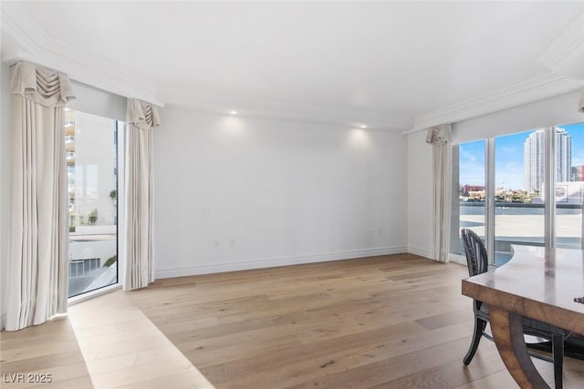 office area with baseboards, a city view, light wood-style flooring, and crown molding