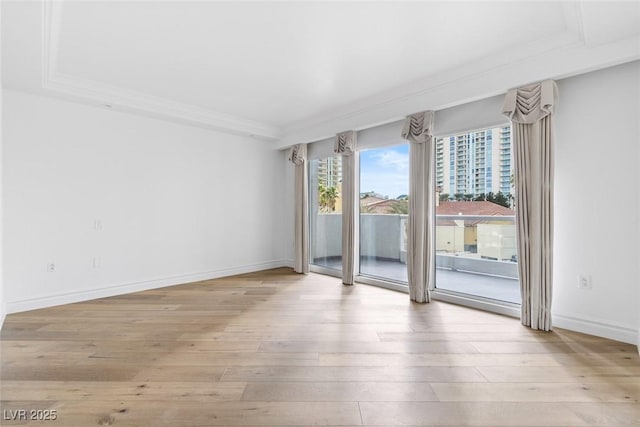 spare room with light wood-style floors, baseboards, and ornamental molding