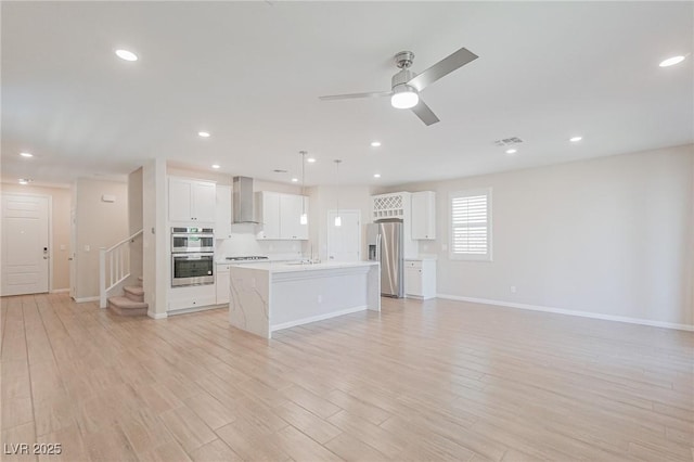 unfurnished living room featuring ceiling fan and light hardwood / wood-style floors