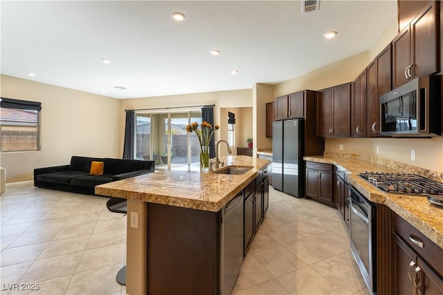 kitchen with sink, dark brown cabinetry, a kitchen island with sink, appliances with stainless steel finishes, and light tile patterned floors