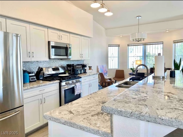 kitchen with white cabinets, appliances with stainless steel finishes, sink, and pendant lighting