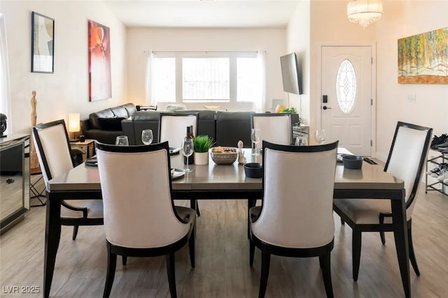 dining space with light hardwood / wood-style floors and a chandelier