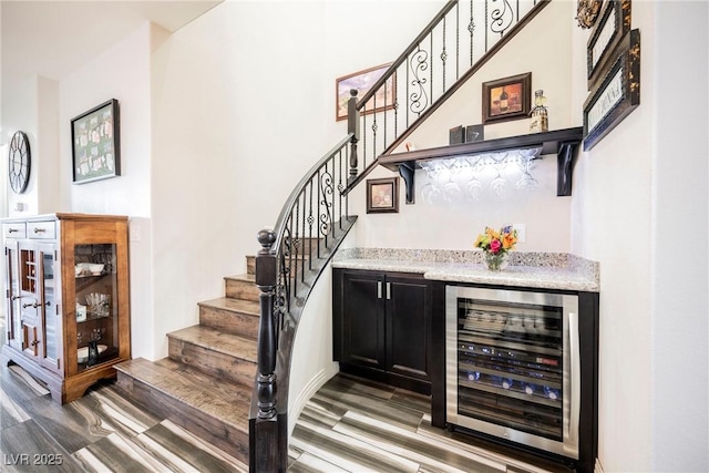 bar with hardwood / wood-style flooring, beverage cooler, and light stone counters