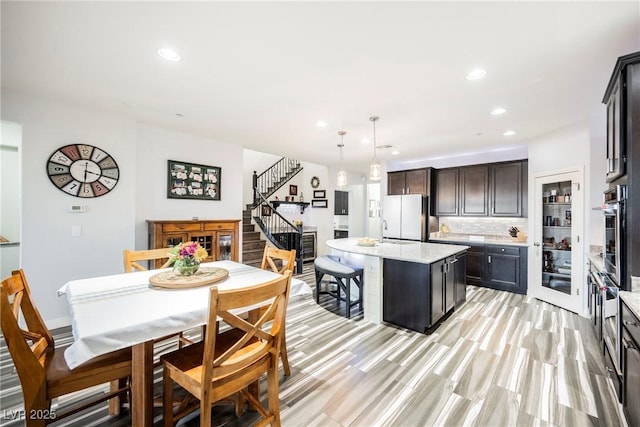 kitchen with a kitchen island, pendant lighting, decorative backsplash, white refrigerator, and stainless steel oven