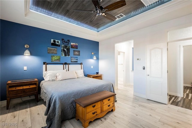 bedroom featuring ceiling fan, a raised ceiling, and light hardwood / wood-style flooring