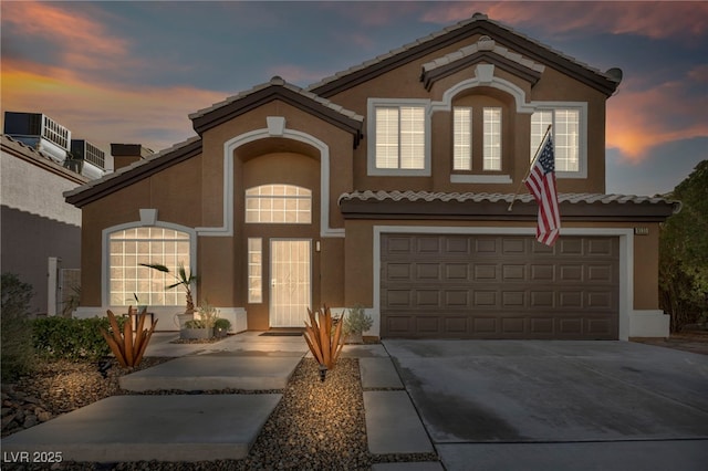 mediterranean / spanish-style house featuring a garage and central AC