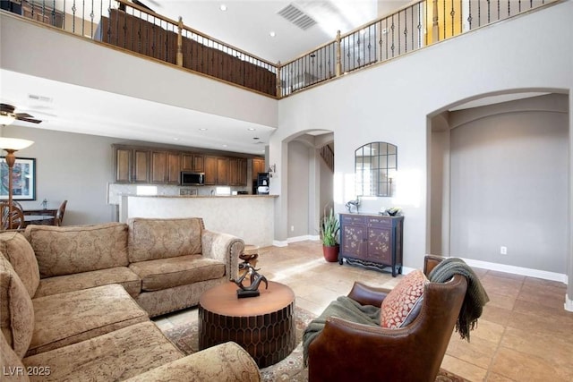 living room featuring ceiling fan and a towering ceiling