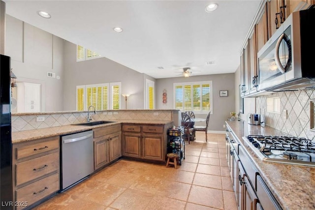 kitchen featuring ceiling fan, backsplash, kitchen peninsula, sink, and stainless steel appliances