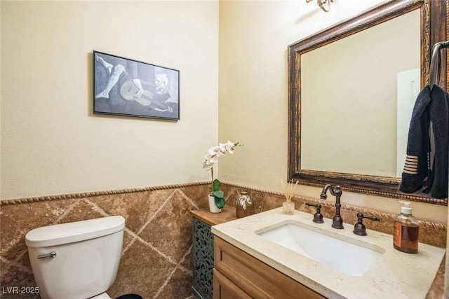 bathroom with tile walls, toilet, and vanity