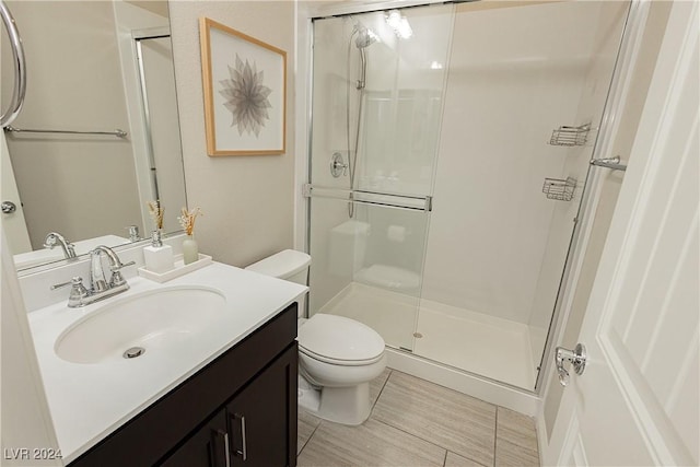 bathroom with toilet, vanity, and a shower with shower door