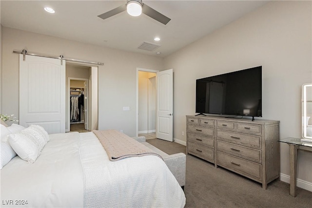 carpeted bedroom featuring ceiling fan, a spacious closet, and a barn door