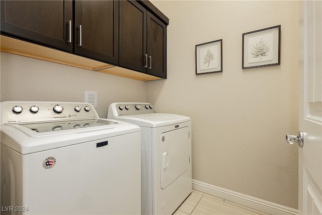 laundry room with cabinets, light tile patterned floors, and independent washer and dryer