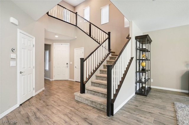 stairway with a towering ceiling and hardwood / wood-style flooring