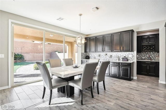 dining space featuring light wood-type flooring and an inviting chandelier