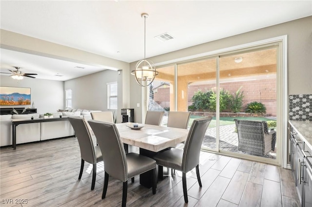 dining room with light wood-type flooring and ceiling fan with notable chandelier