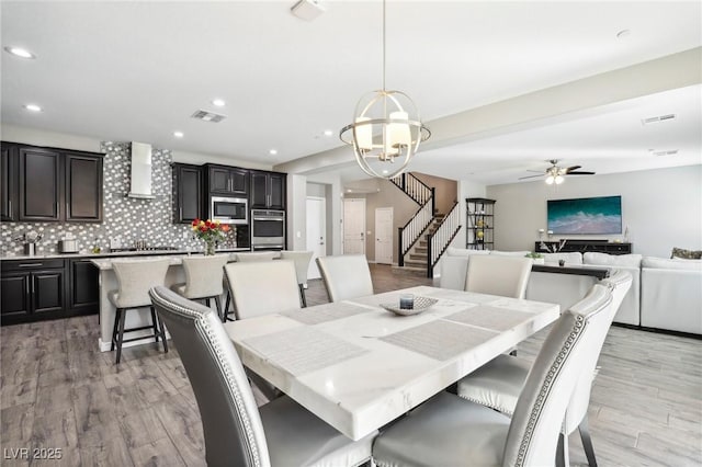 dining space featuring ceiling fan with notable chandelier and light hardwood / wood-style flooring