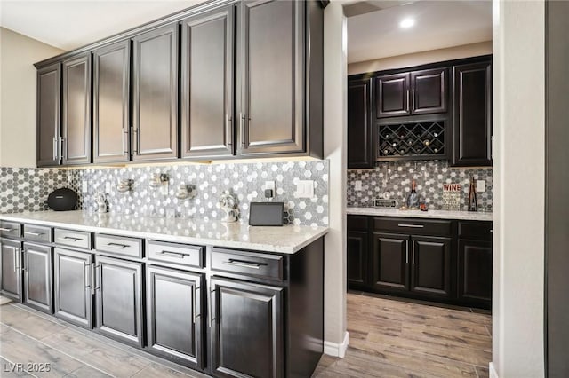 kitchen featuring decorative backsplash, light hardwood / wood-style floors, and light stone countertops