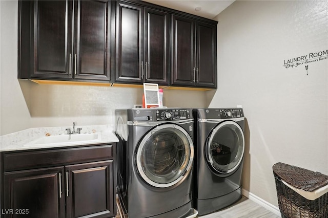 washroom featuring sink, washing machine and clothes dryer, and cabinets