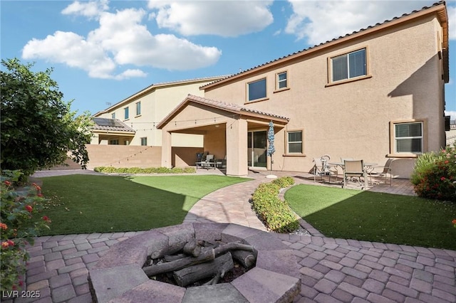 back of property featuring a yard, a patio, and a fire pit