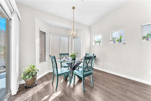 dining area featuring a notable chandelier, dark wood-type flooring, and vaulted ceiling