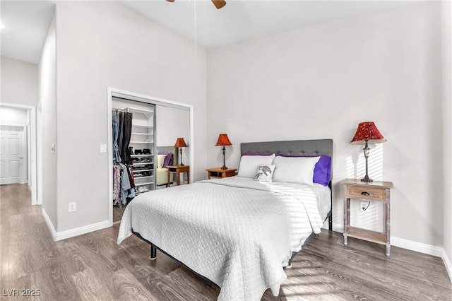 bedroom with ceiling fan, wood-type flooring, a closet, and a high ceiling